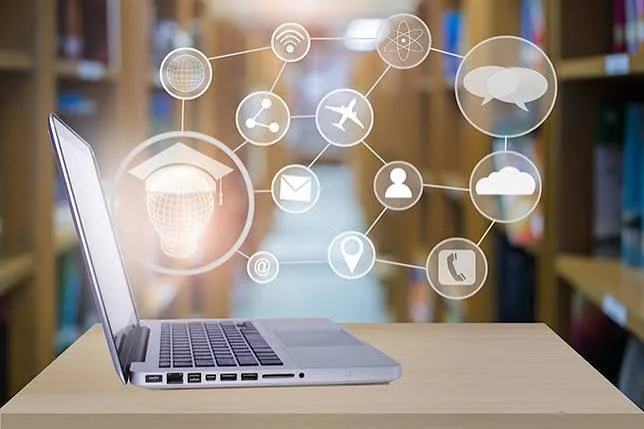 Laptop on a library desk with floating icons for learning, email, location and cloud
